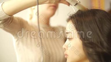 理发师用热卷发为女人做卷发，美容工作室里的女人，美容和时尚生意
